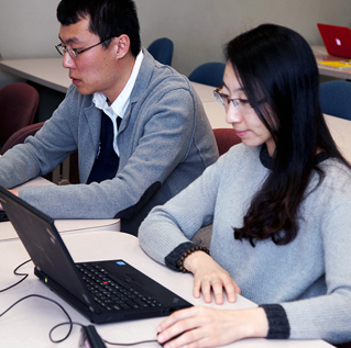 International students, man 和 woman, on their laptops
